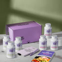 A product bundle display for GleeFull Supplements on a marble surface against a green background. The layout includes a large purple shipping box featuring the slogan 'FEEL LIKE YOURSELF AGAIN.', three white bottles of Over 30 Hormone Support and three white bottles of Meno Joint Relief, a purple branded pen, a matching notepad that reads 'REMINDERS WHEN I'M HAVING A MENOPAUSE MOMENT', and a recipe booklet titled 'THE MENOPAUSE Recipes'