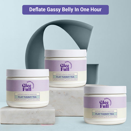 Three white GleeFull Flat Tummy Tea powder jars/tubs on marble blocks against a light blue background. Purple banner reads: 'Deflate Gassy Belly In One Hour'. Labels read 'Supports Healthy Digestion, Flat Tummy Tea, Net Wt. 4.23 oz (120 g)'.