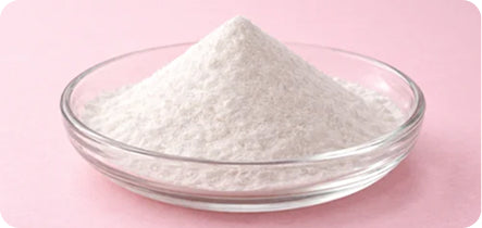 White powder in a glass bowl on a pink background